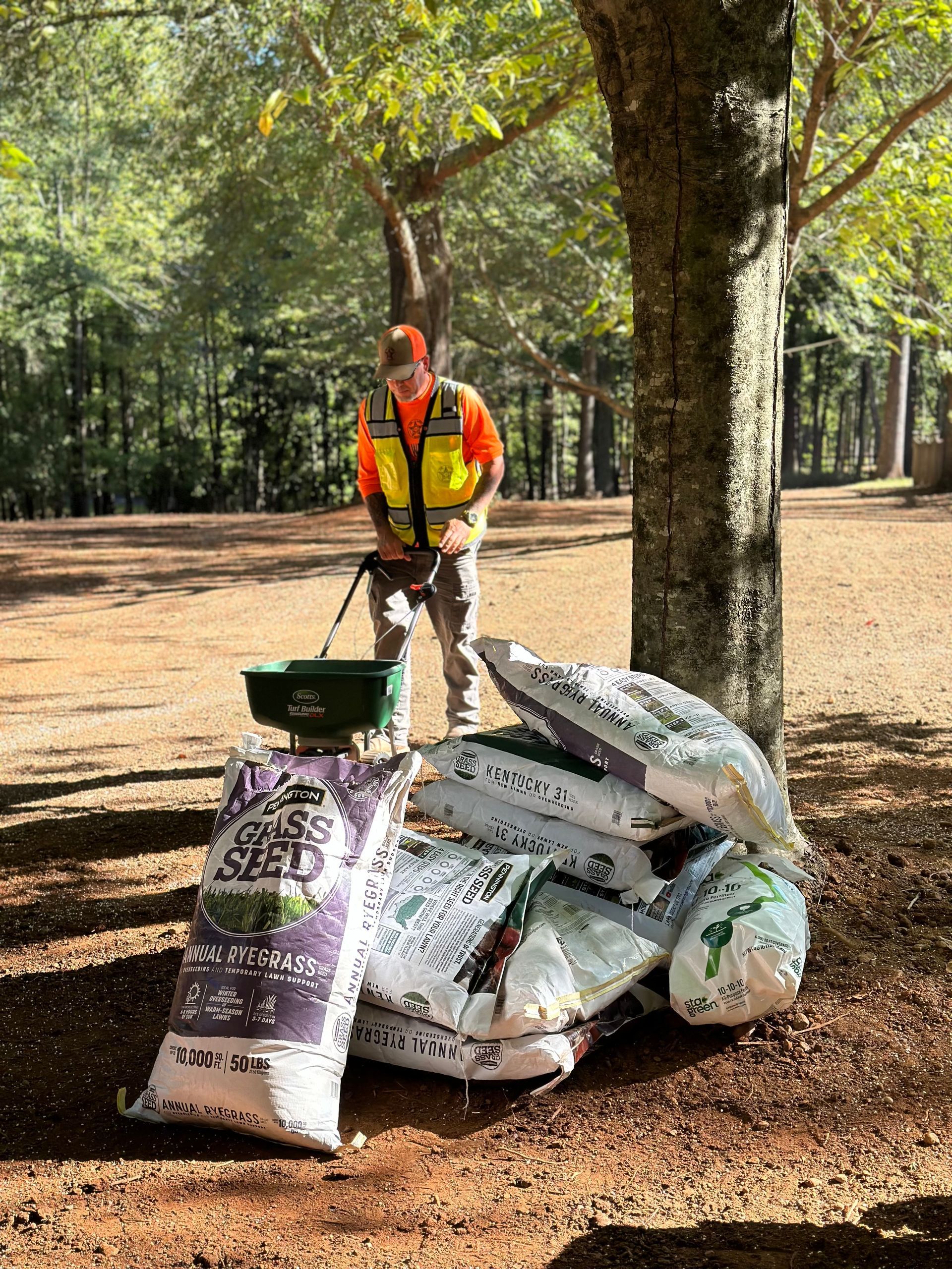 A man is standing next to a pile of bags of mulch.