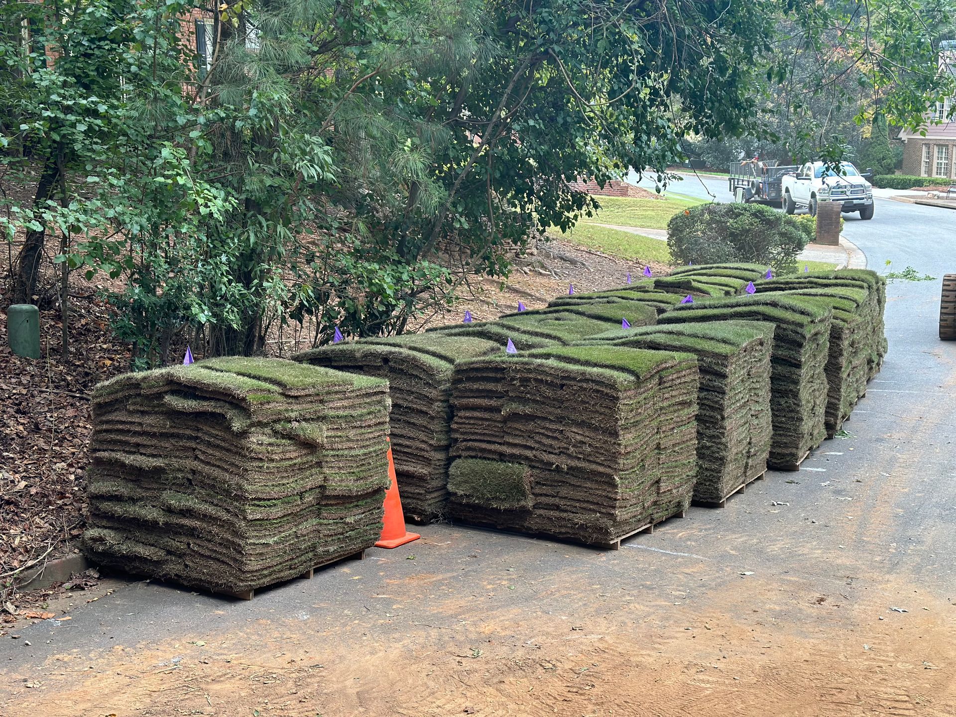 A bunch of rolls of turf are sitting on the side of a road.