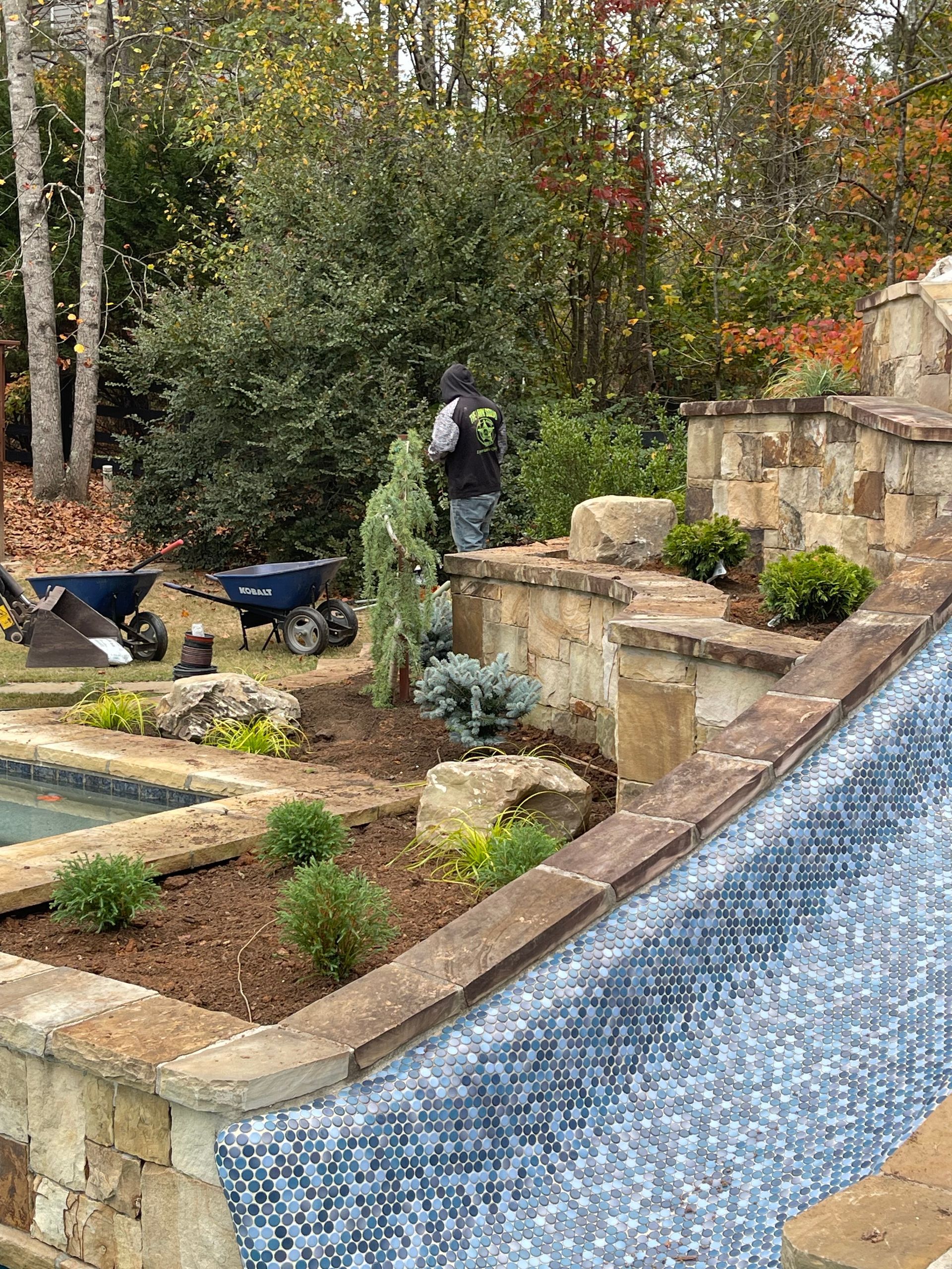 A man is working on a waterfall next to a pool.