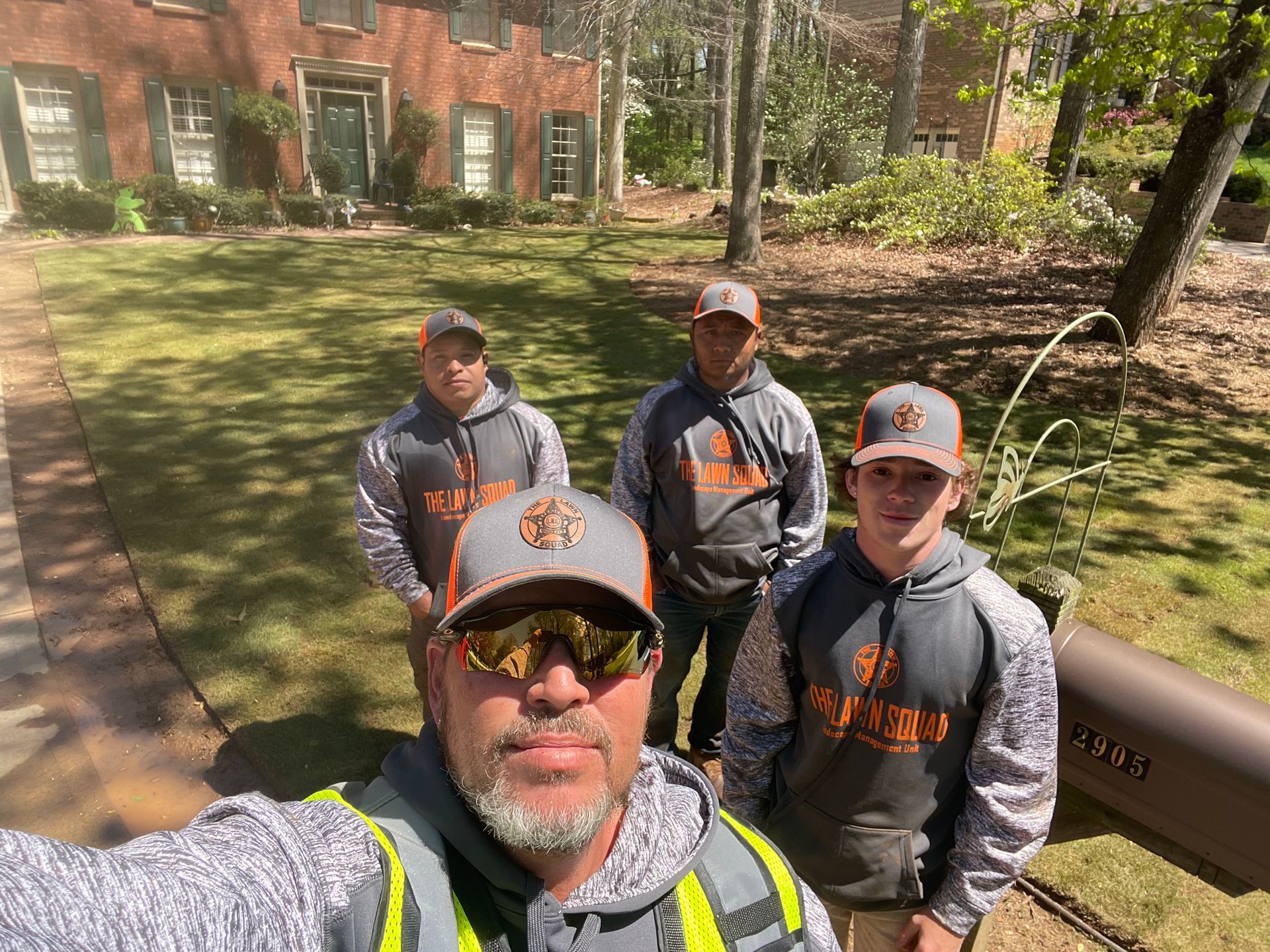 A group of men are standing in front of a house taking a selfie.