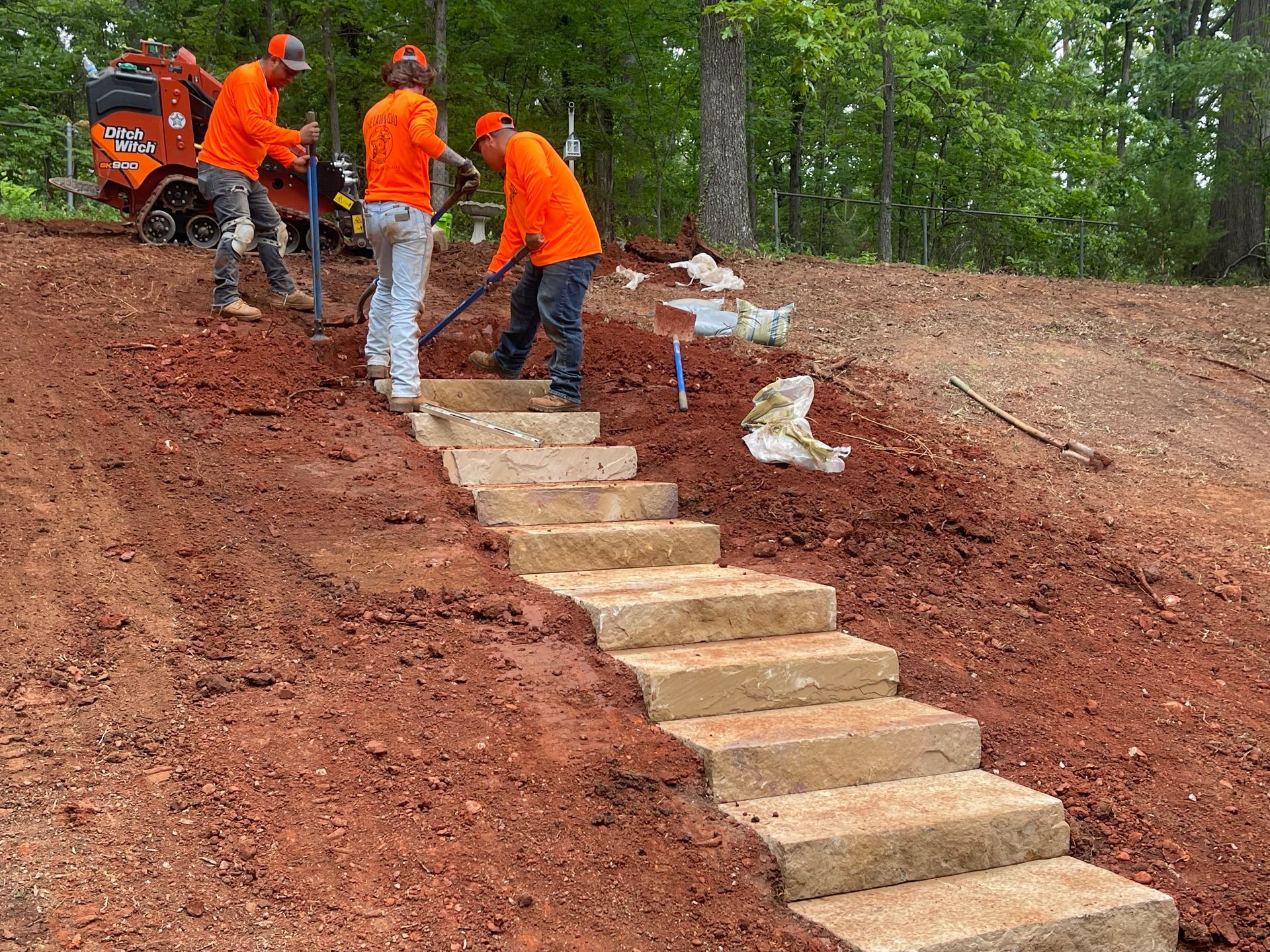 A group of men are working on a set of stairs in the dirt.