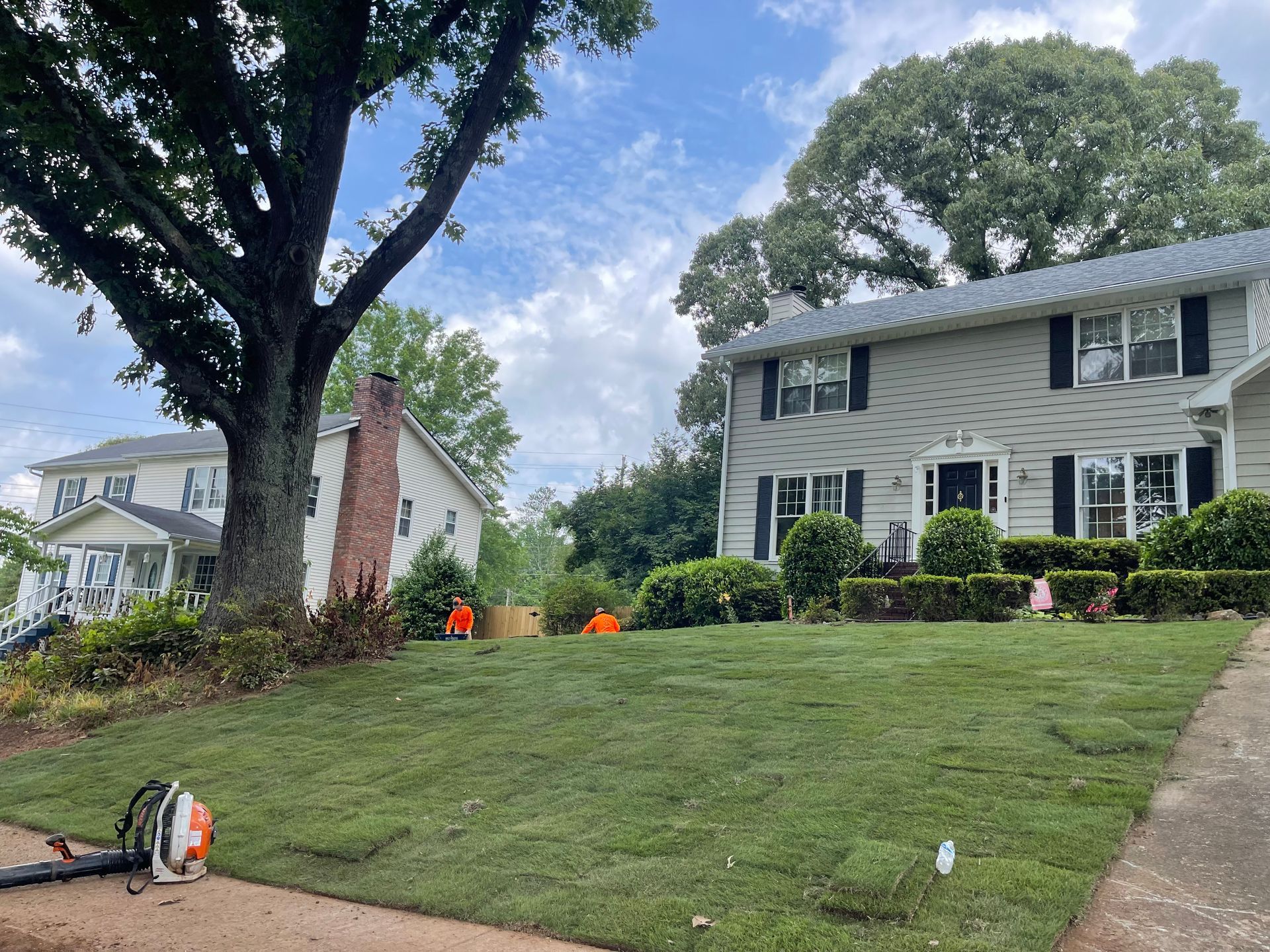 A lawn mower is sitting on the sidewalk in front of a house.