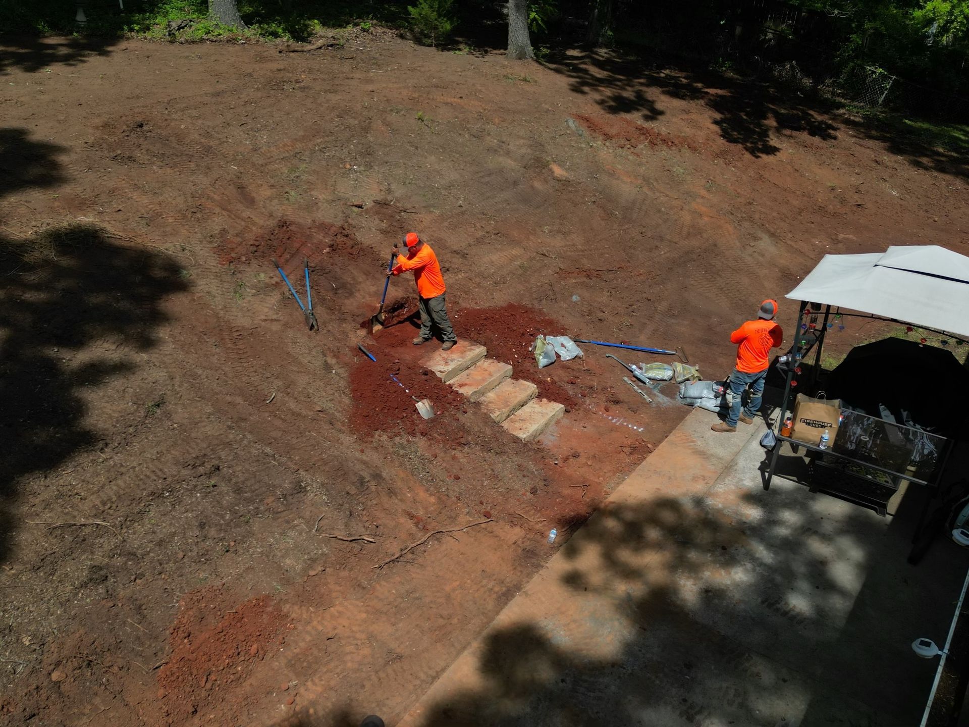 A couple of men are working on a dirt hill.