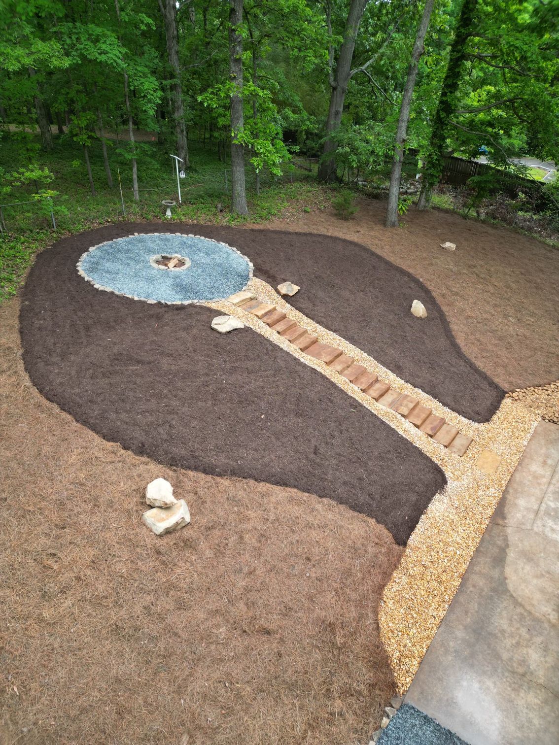 An aerial view of a garden with a fire pit in the middle of it.