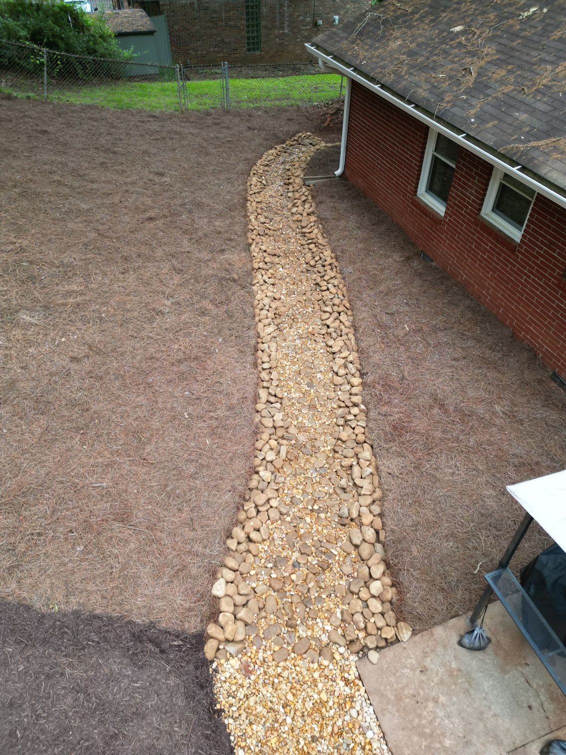 A walkway made of gravel is leading to a brick house.