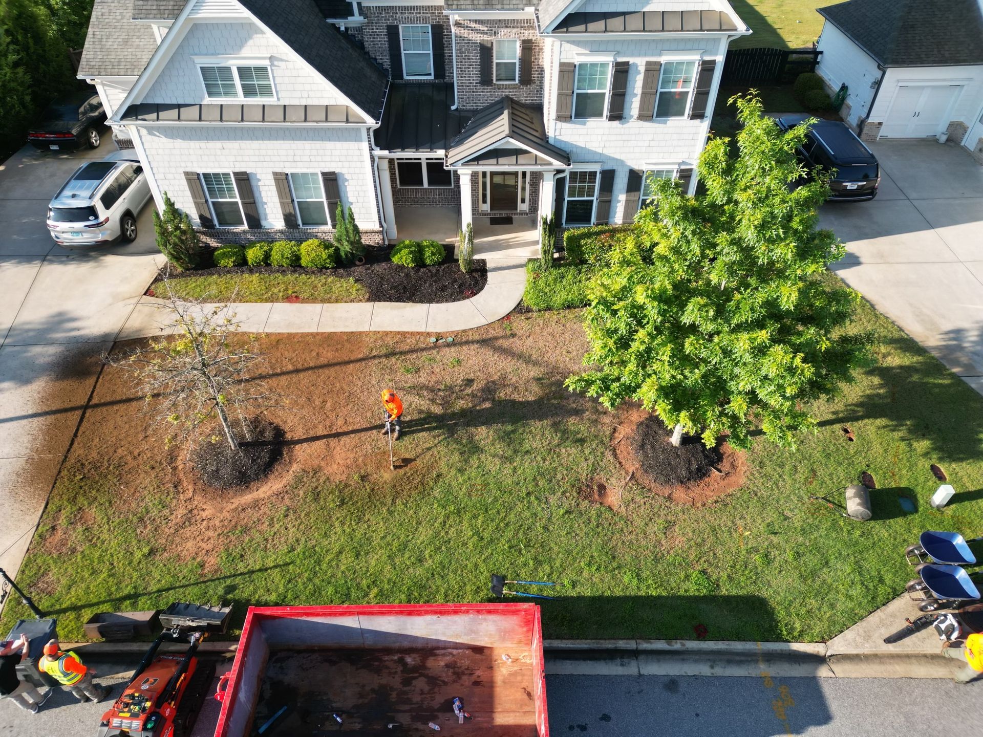 An aerial view of a house with a dumpster in front of it.