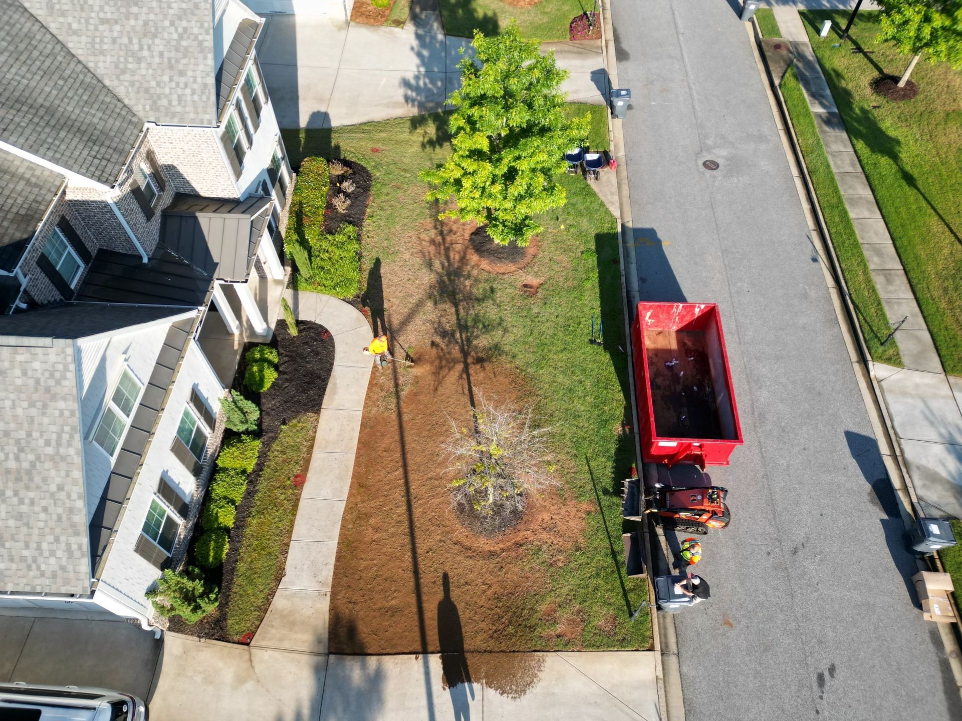 An aerial view of a red dumpster in front of a house.