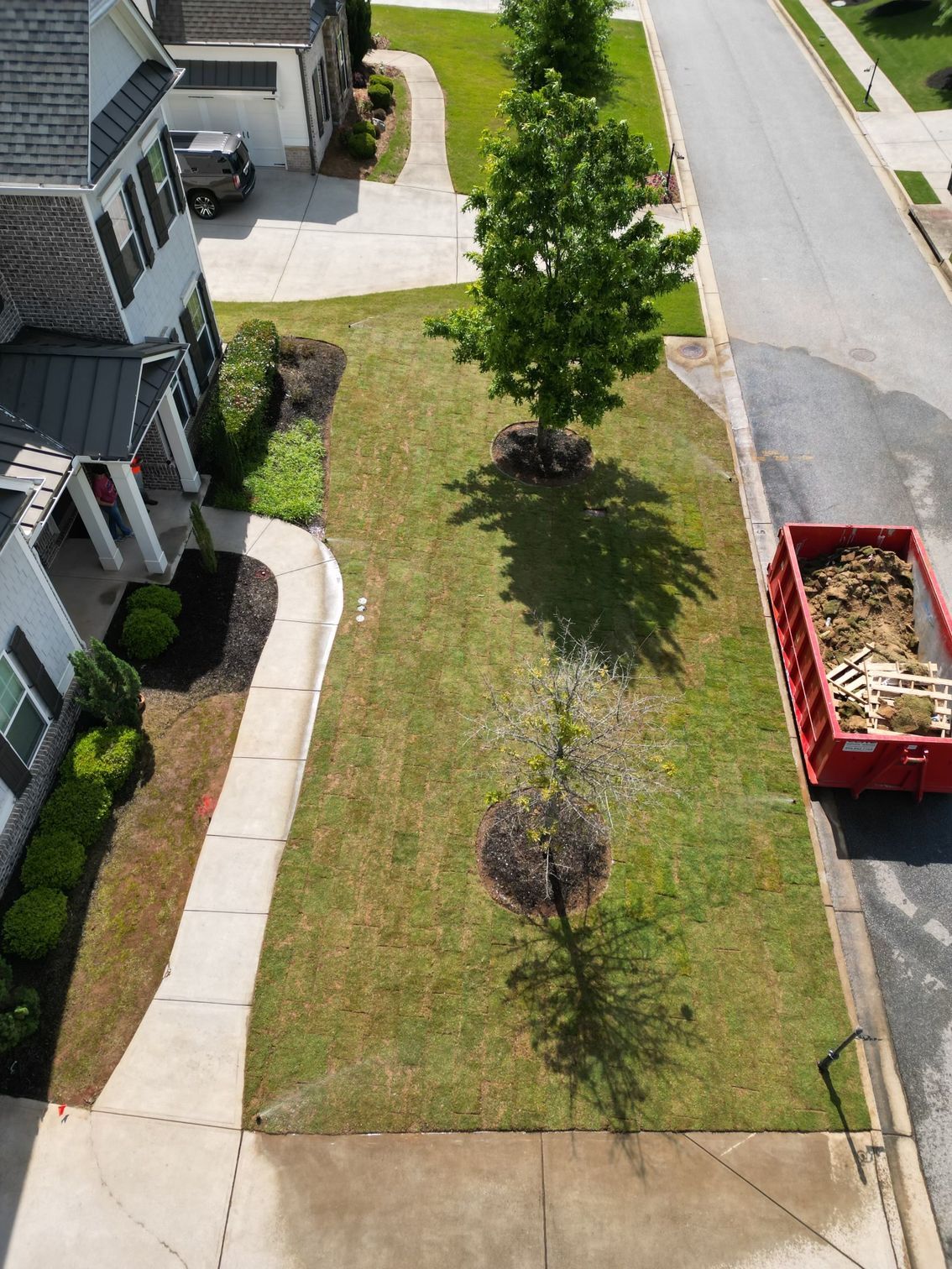An aerial view of a house with a red dumpster in front of it.