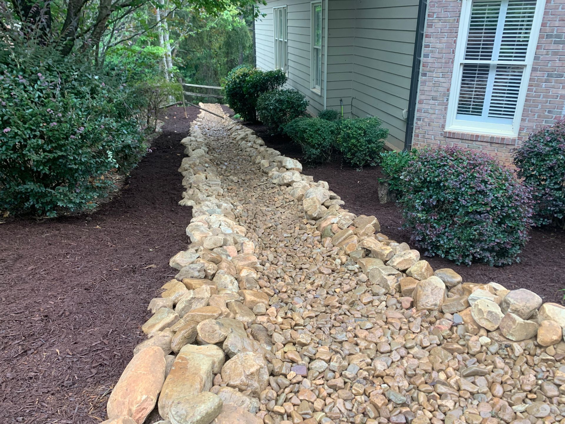 A path made of rocks and mulch is leading to a house.