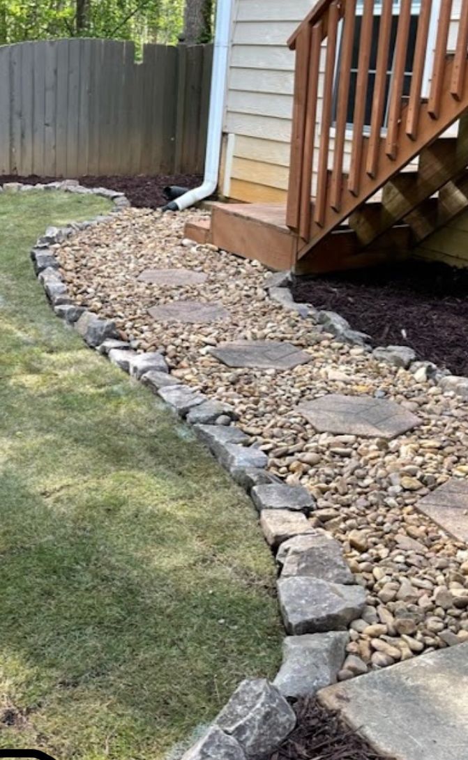 A stone walkway leading to a deck next to a house.