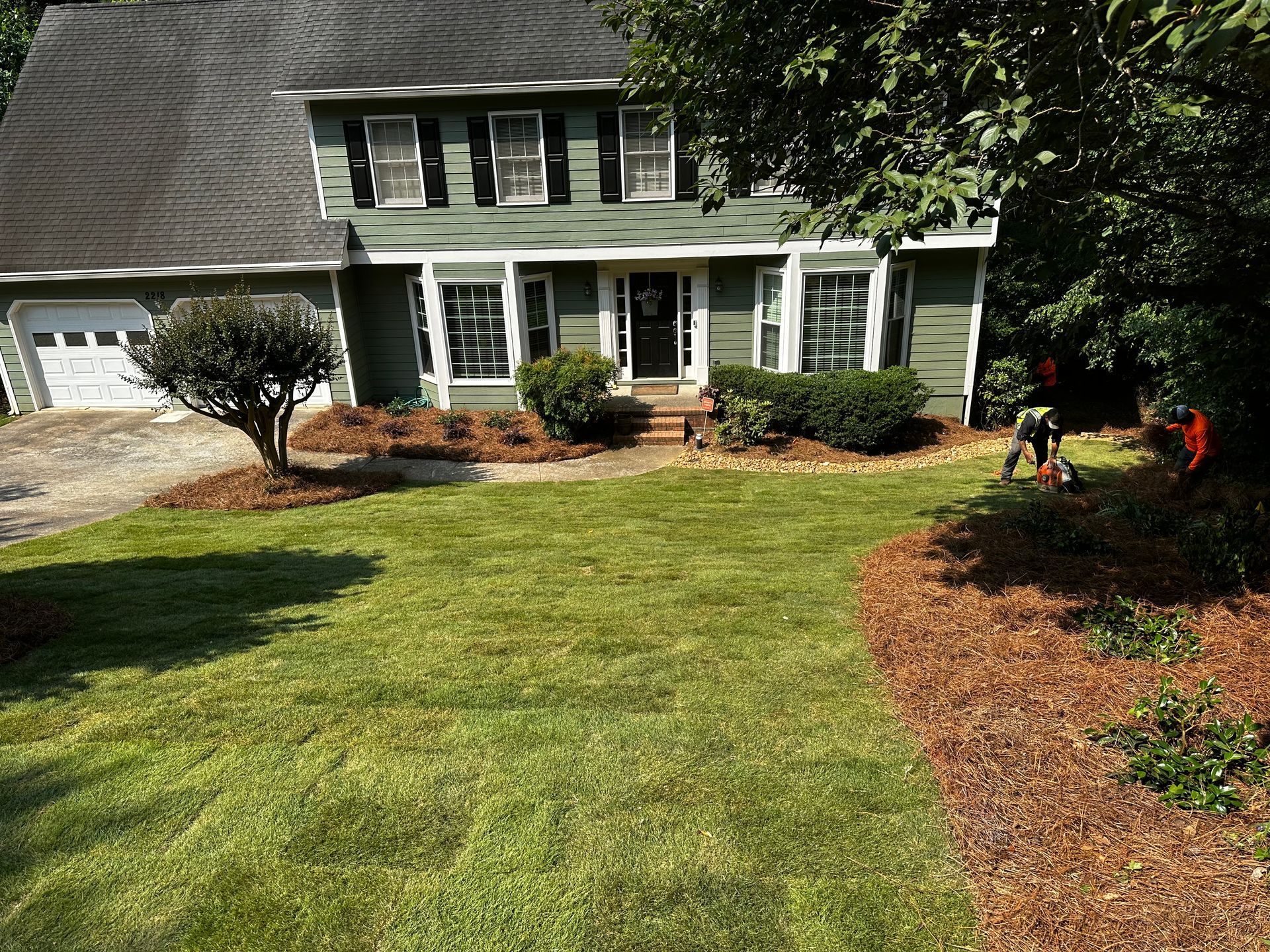 A green house with a lush green lawn in front of it.