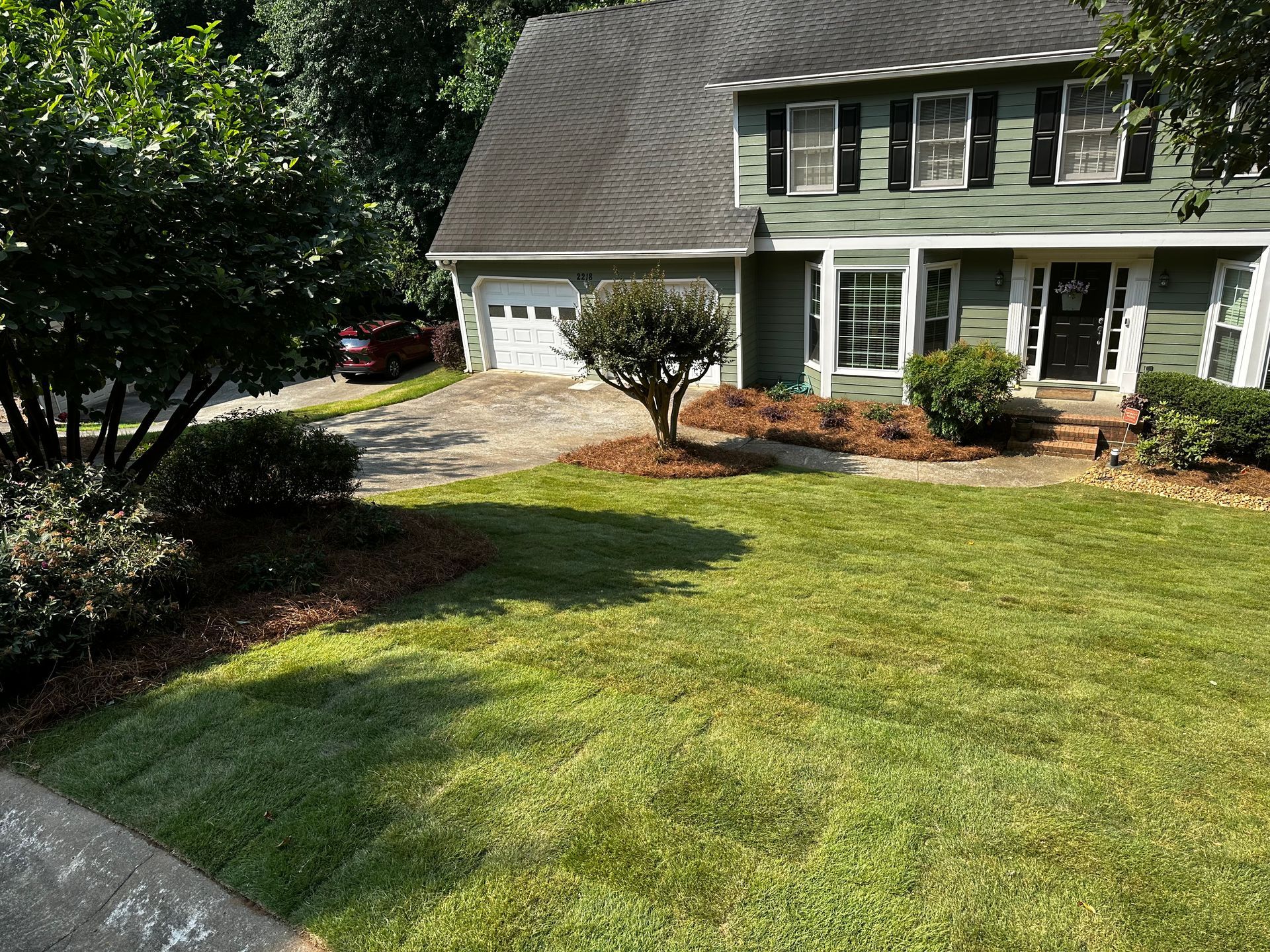 A green house with a lush green lawn in front of it.