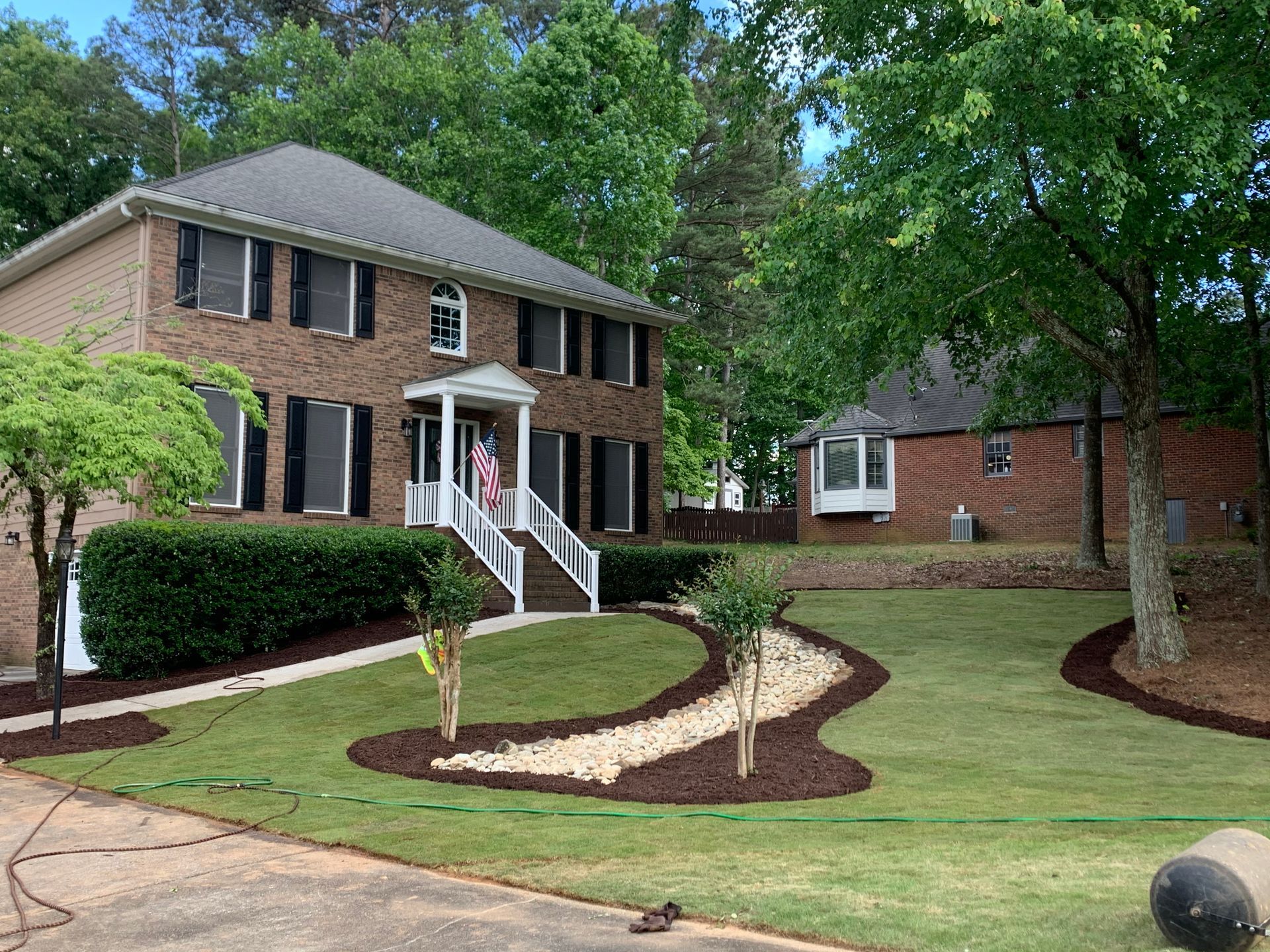 A large brick house with a lush green lawn in front of it.