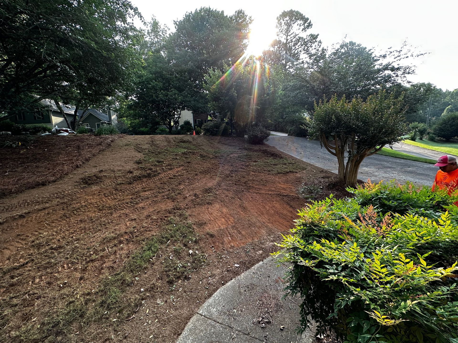 A man is standing in the middle of a dirt field next to a road.