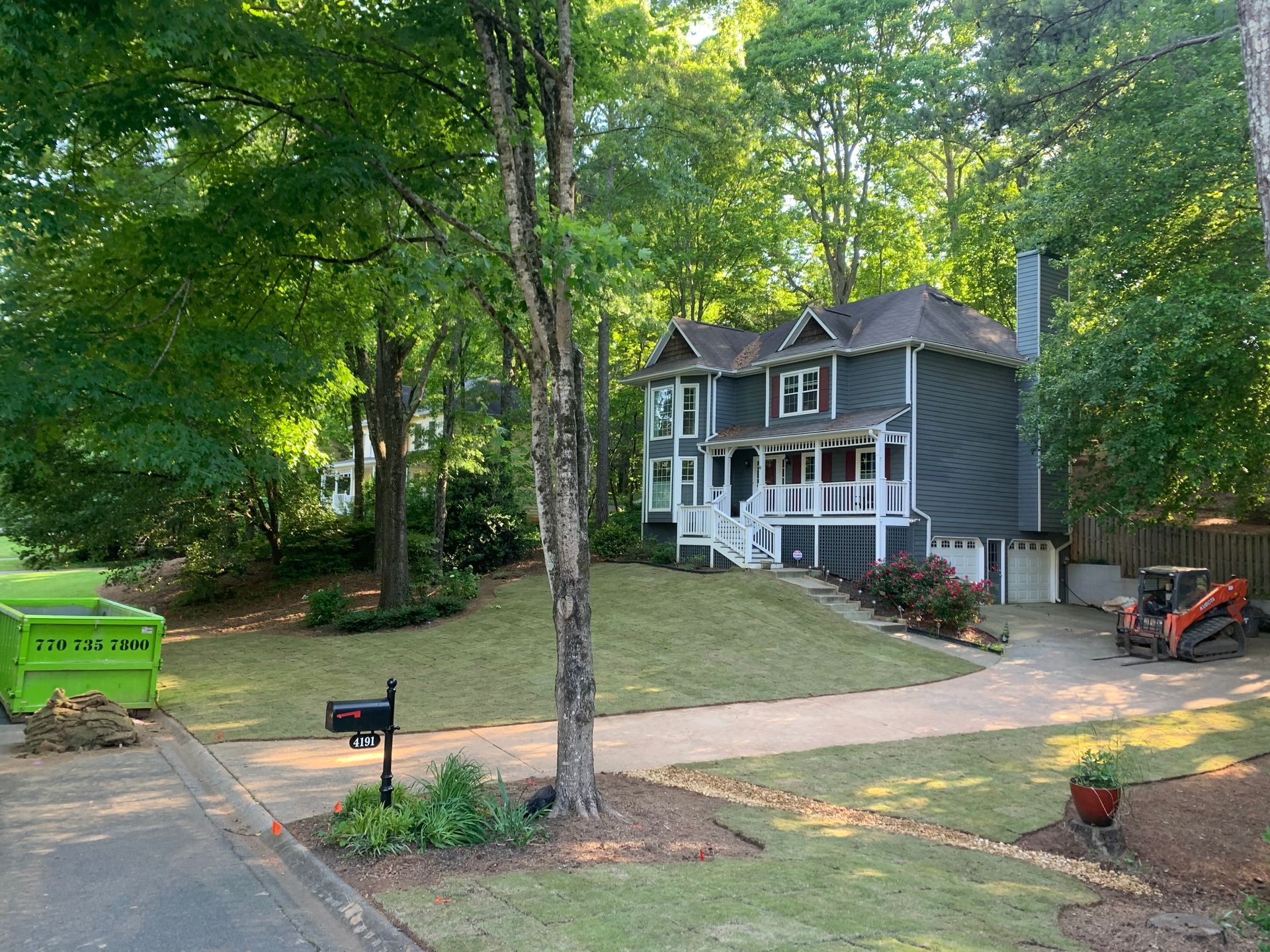 A large house with a green dumpster in front of it.