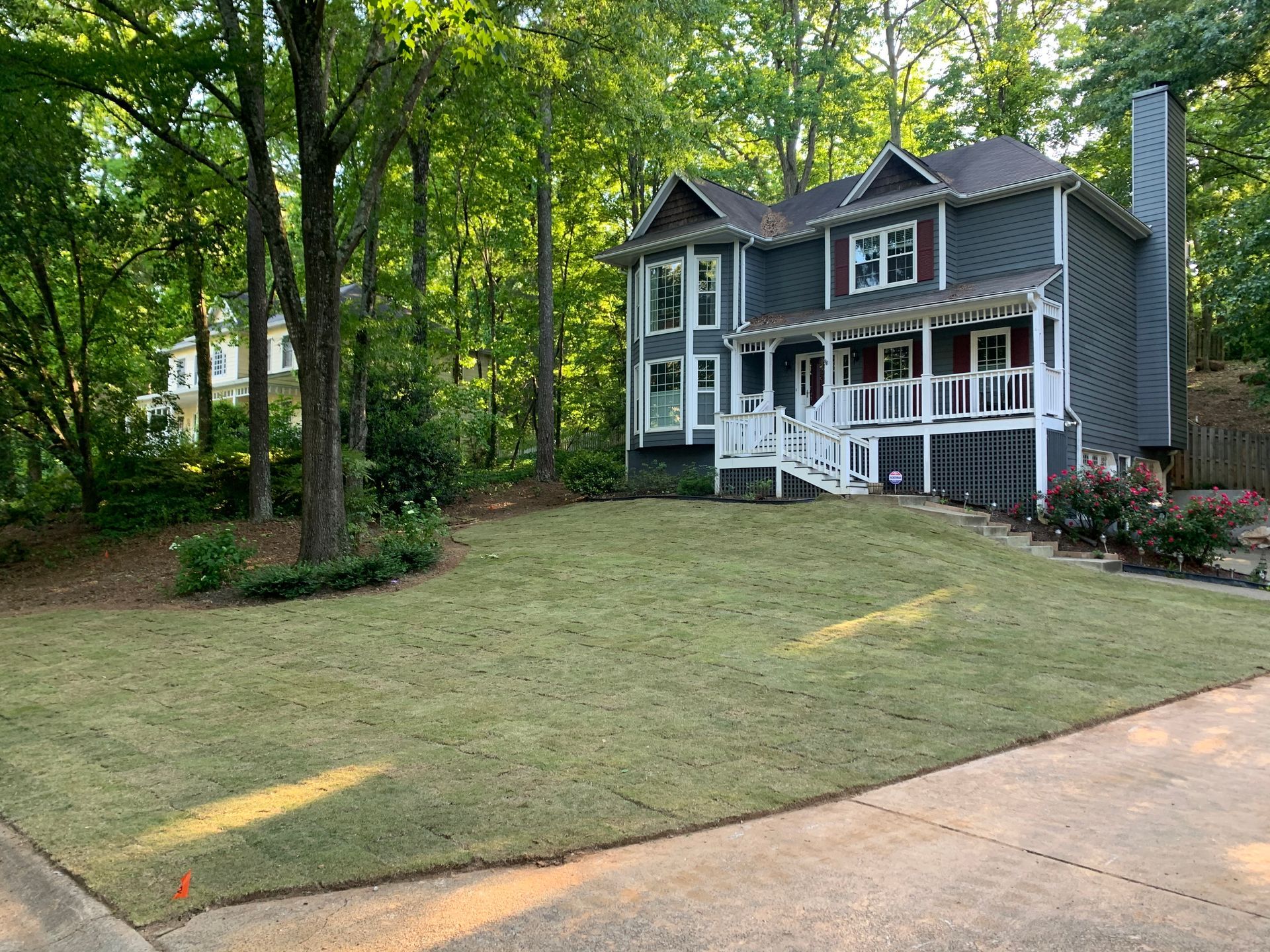 A large house with a large lawn in front of it surrounded by trees.