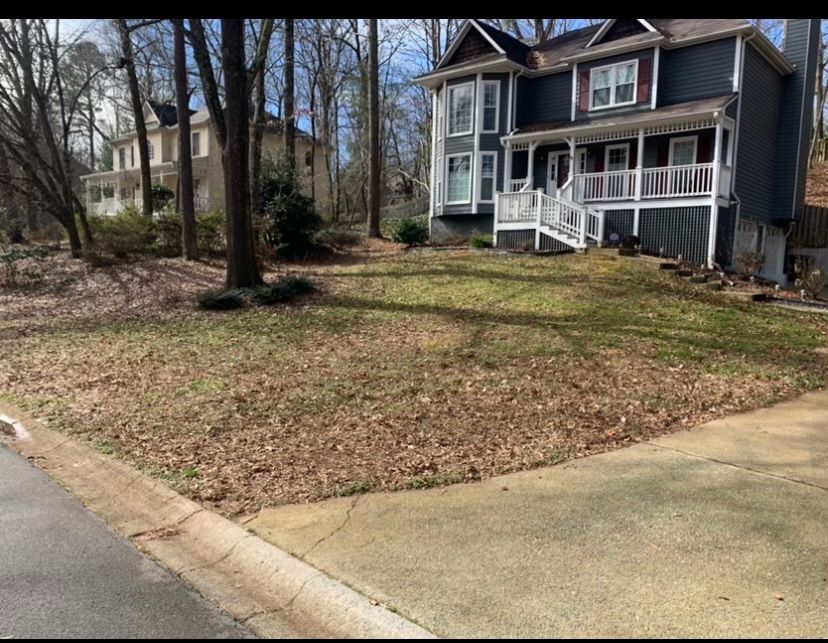 A large house with a large lawn and a driveway in front of it.