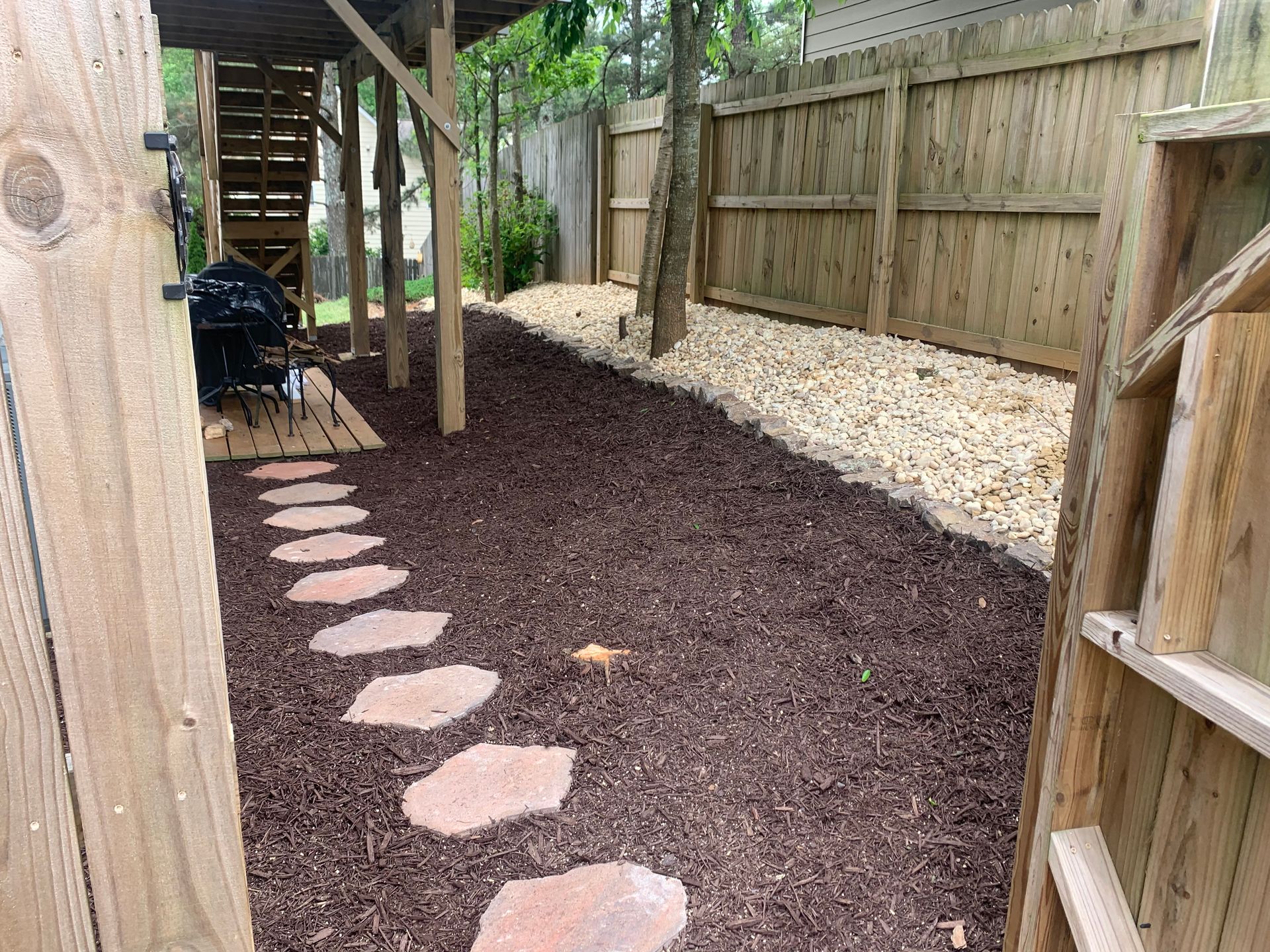 A path with stepping stones leading to a wooden fence.