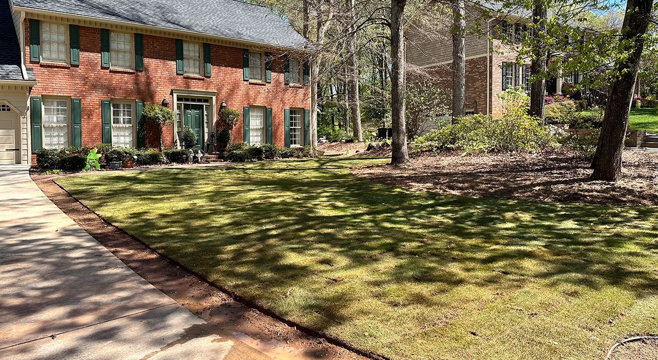 A large brick house with a lush green lawn in front of it.