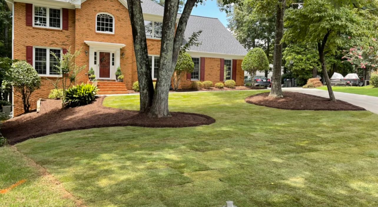 A large brick house with a lush green lawn in front of it.