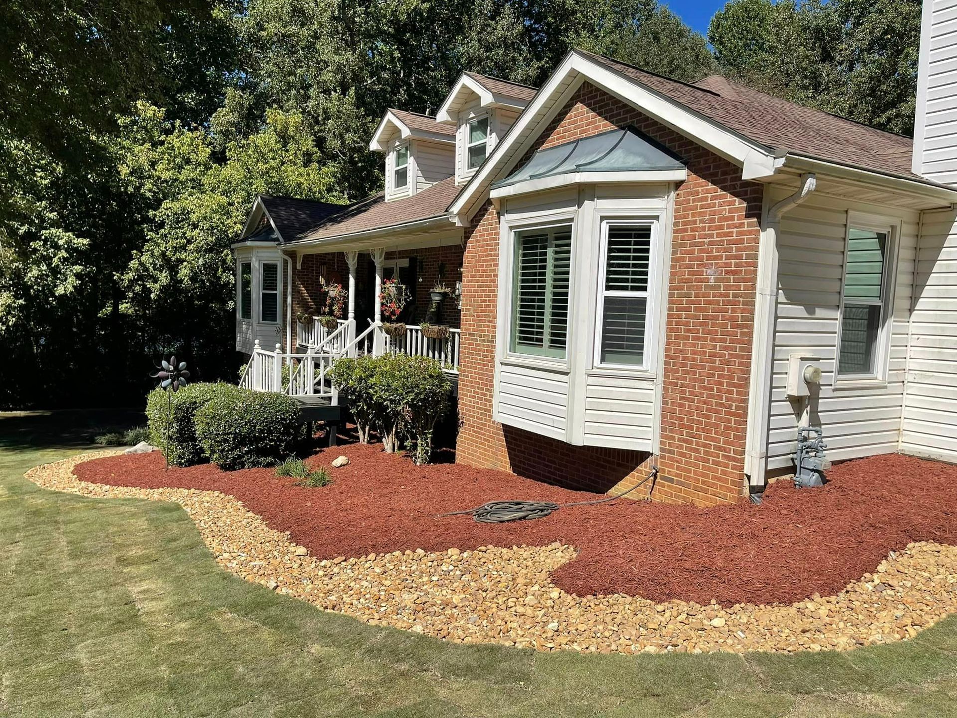 A brick house with a large bay window and a lush green yard.