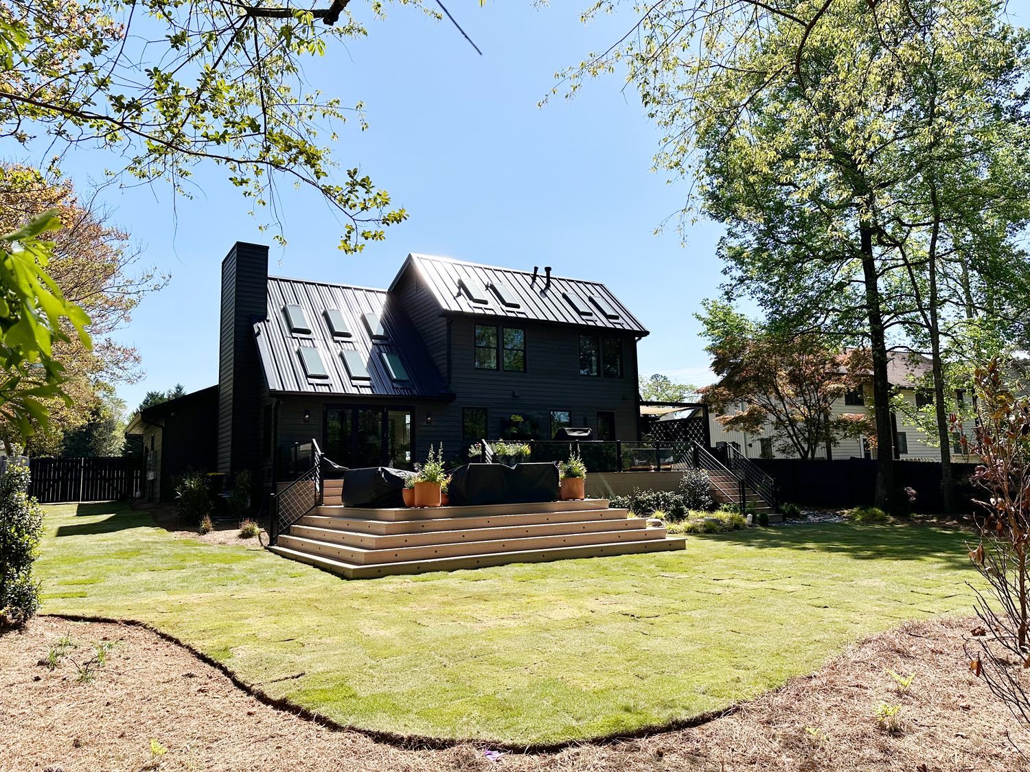 A large black house with a large lawn in front of it.