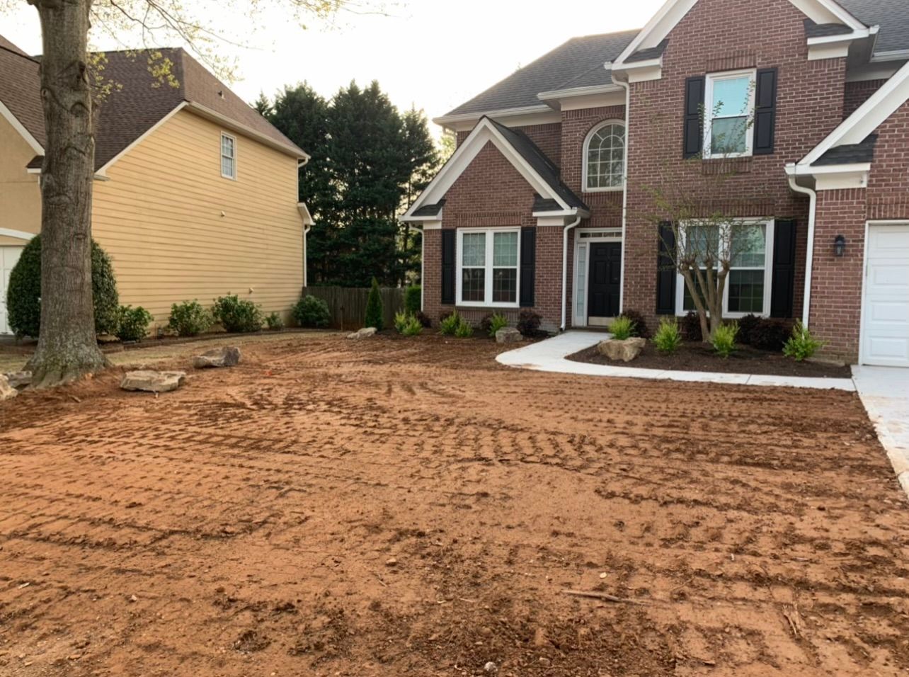 A large brick house with a lot of dirt in front of it.