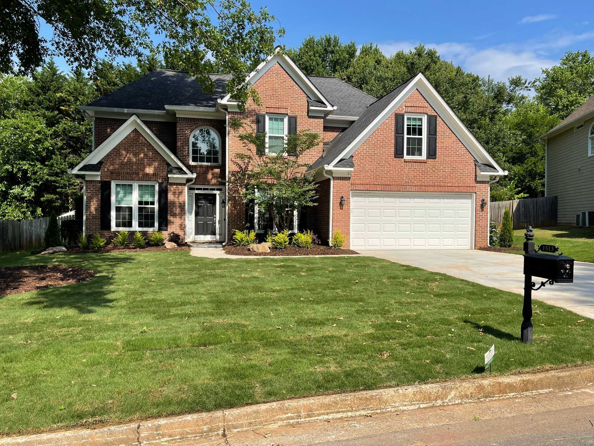 A large brick house with a large lawn and a mailbox in front of it.