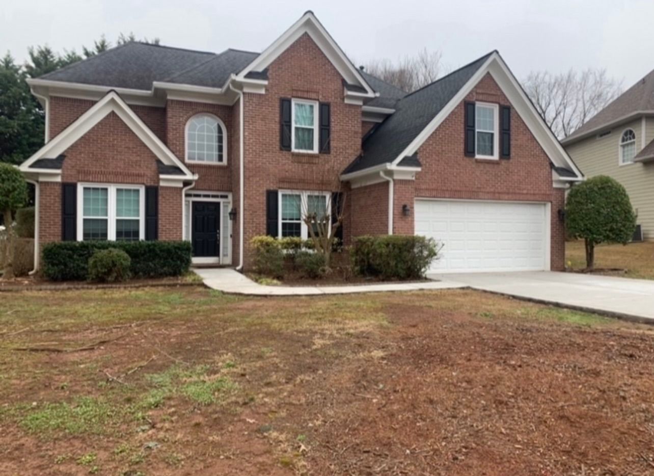 A large brick house with a white garage door and black shutters.