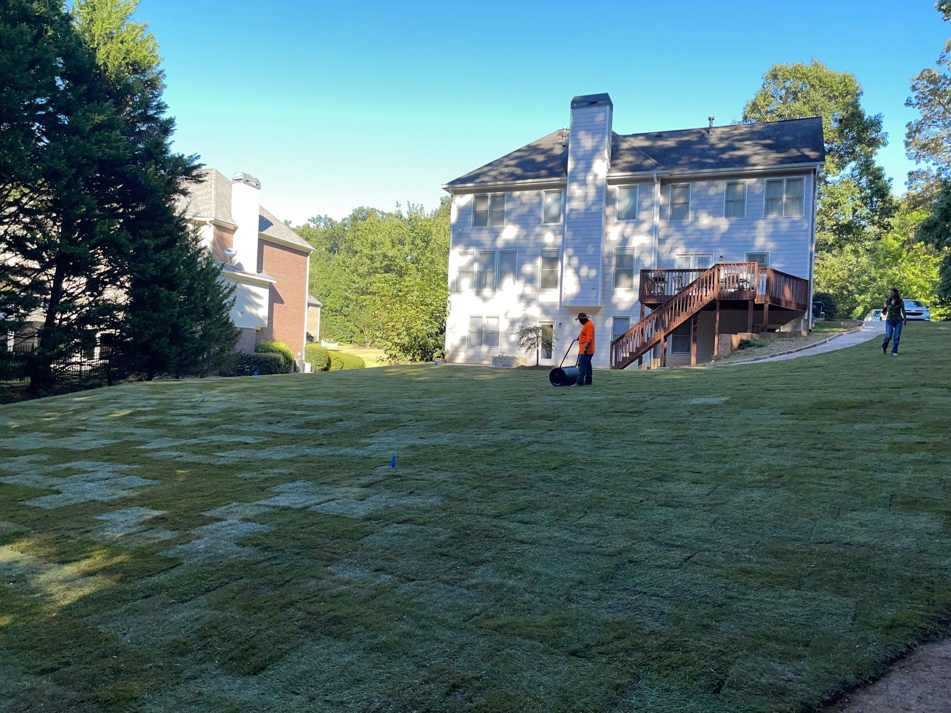 A man is mowing a lush green lawn in front of a house.