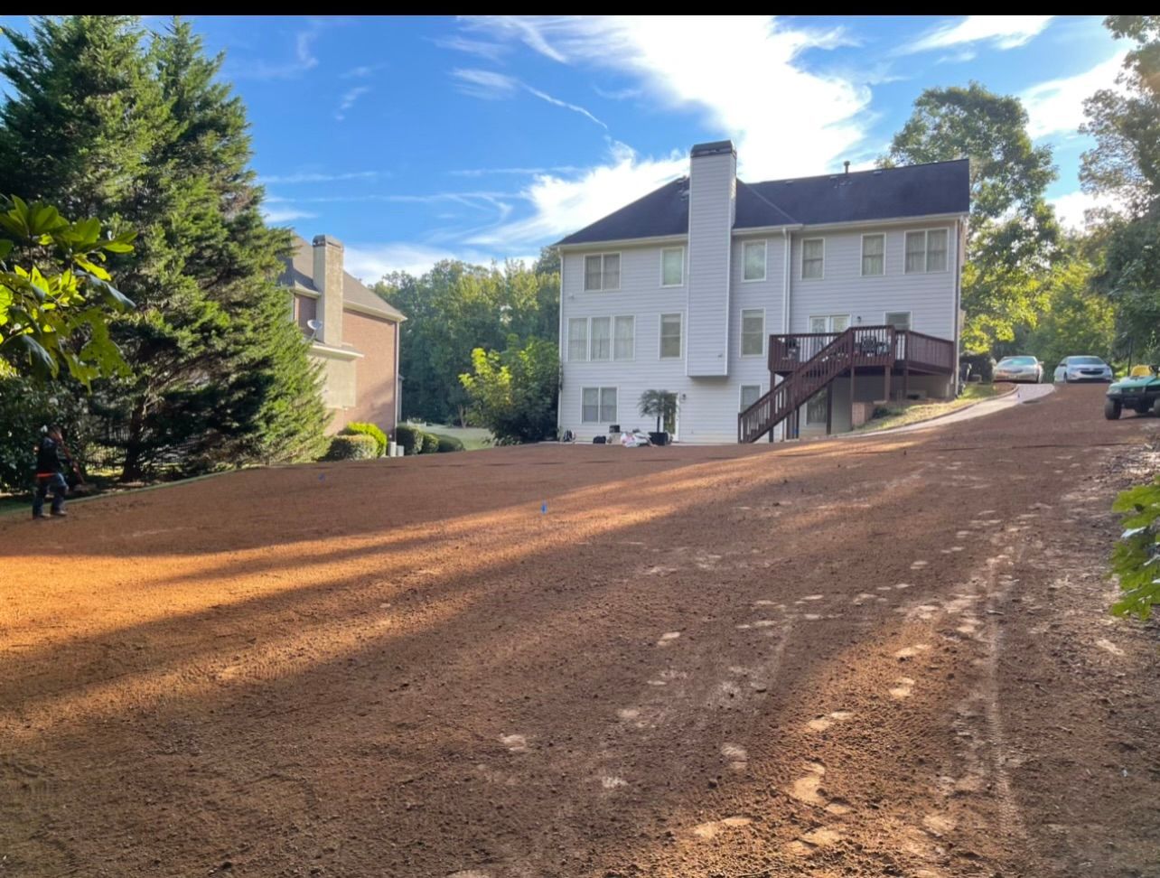 A large white house is sitting on top of a dirt hill.