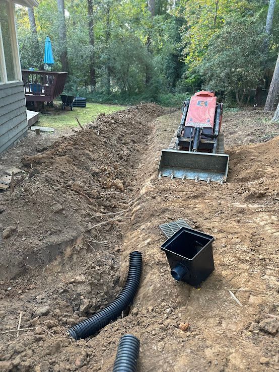 A bulldozer is digging a hole in the dirt in a backyard.
