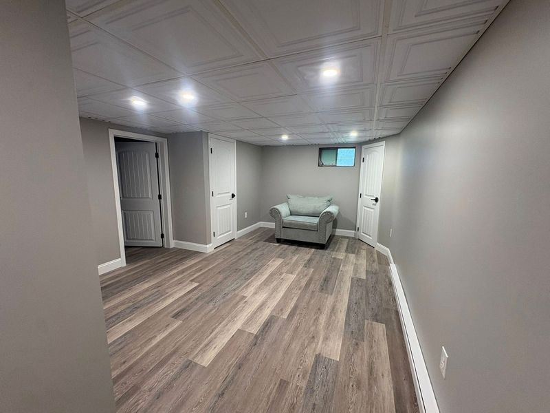 Finished basement with gray walls, wood-look flooring, and a blue armchair.