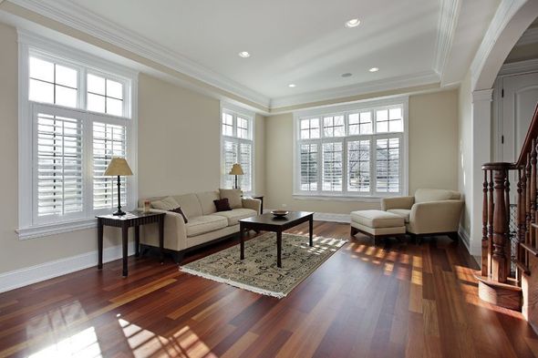 Living room with cream walls, wood floors, large windows, sofa, chair, and coffee table.