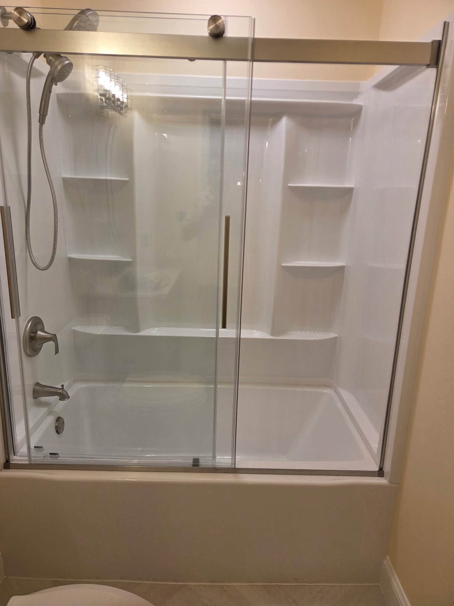 Bathroom shower stall with sliding glass doors, built-in shelves, and chrome fixtures