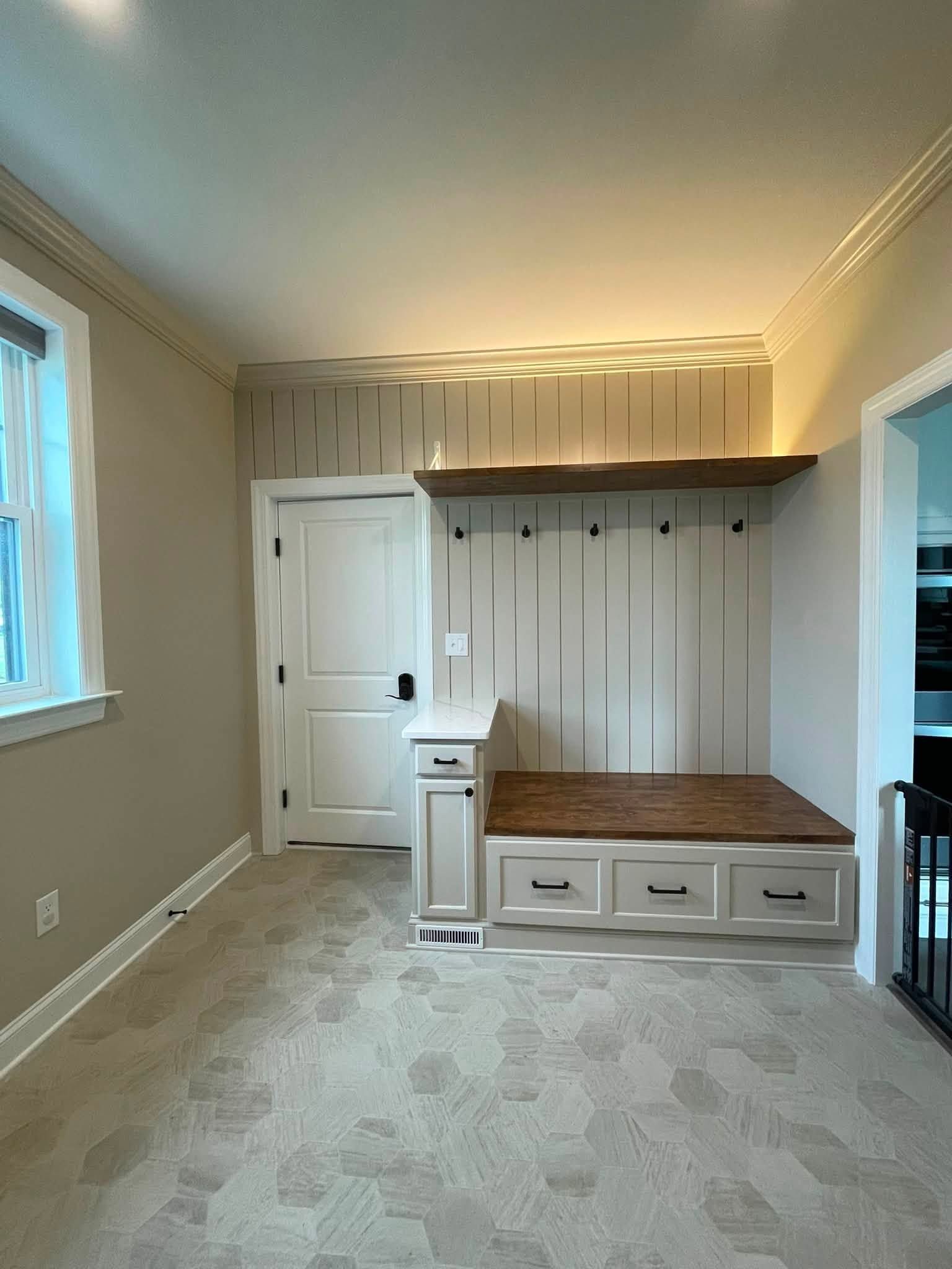 Empty beige bedroom with built-in storage, white door, and light carpet near a window