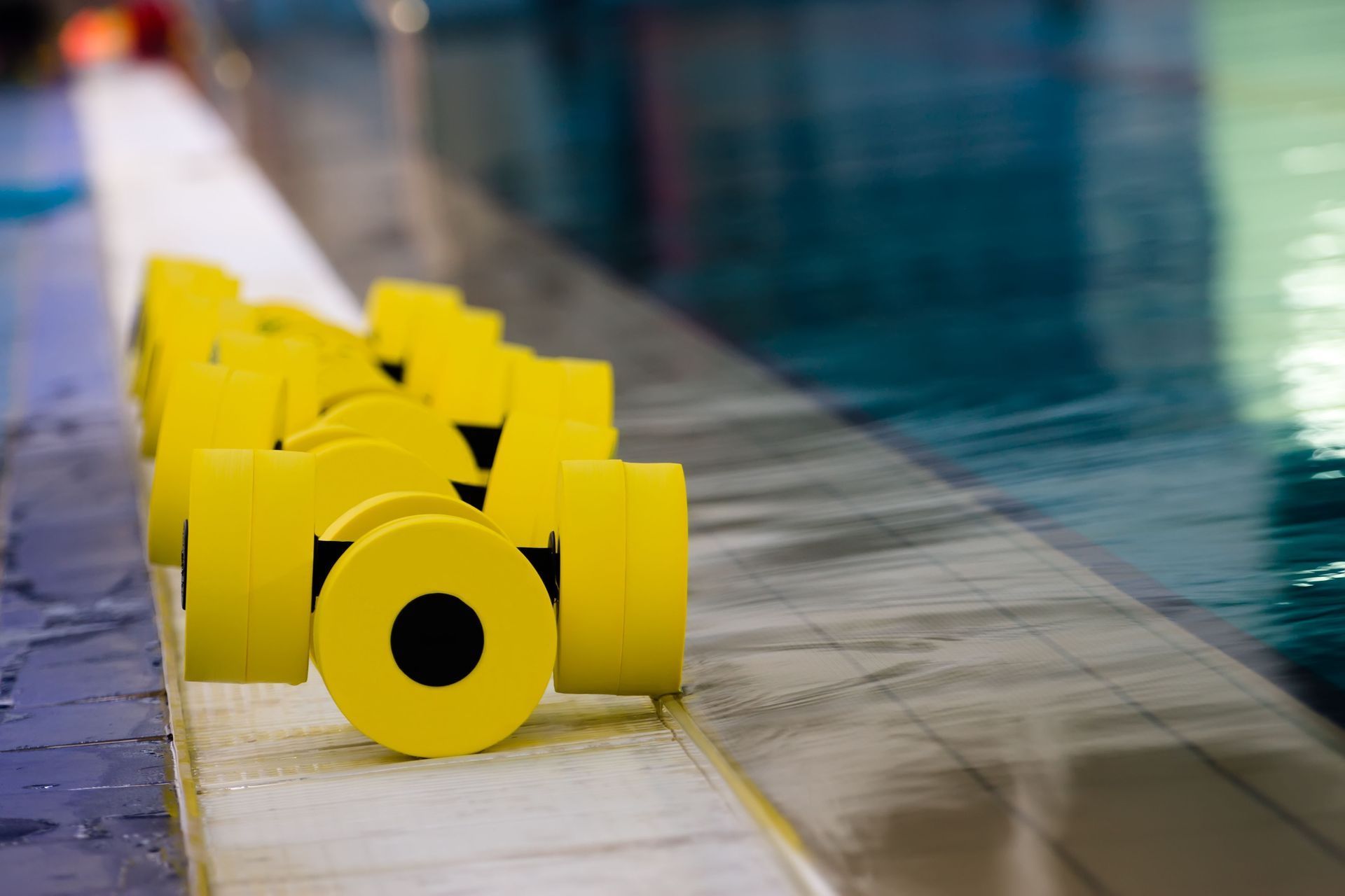 Yellow swim lane markers lined up beside an indoor pool