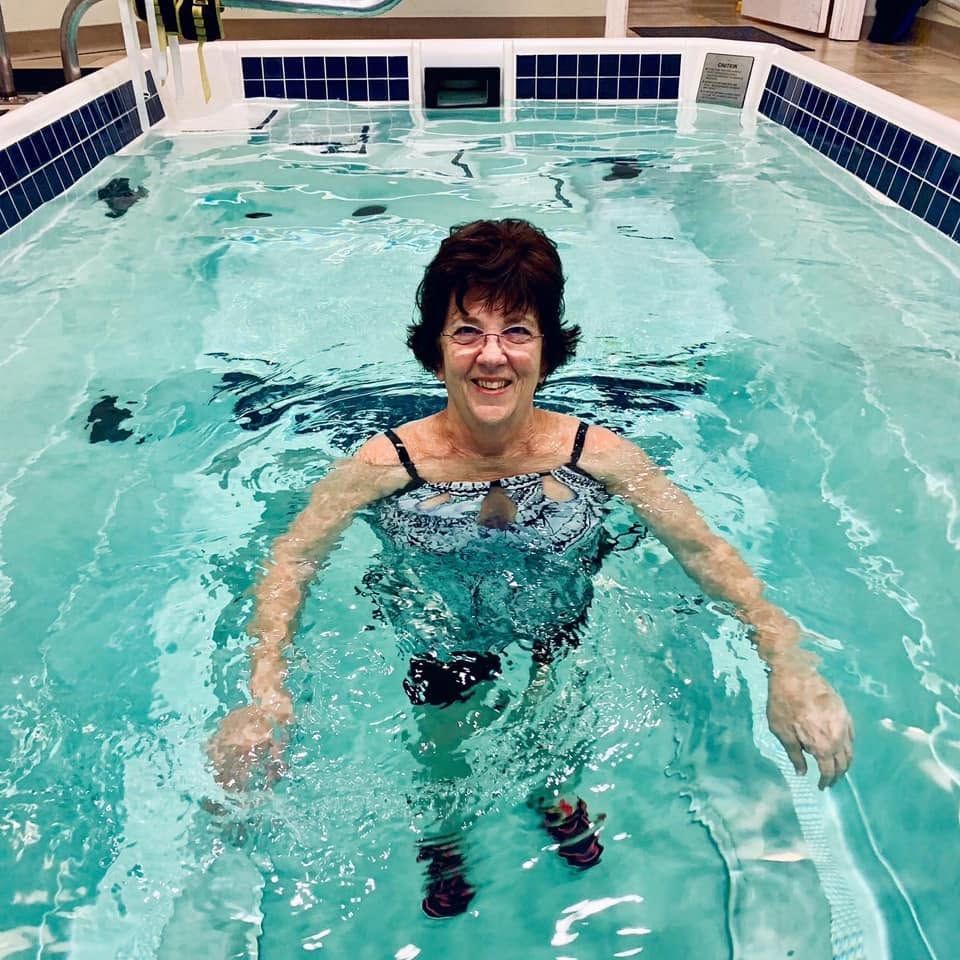Woman smiling in an indoor pool, treading water in a turquoise swim lane
