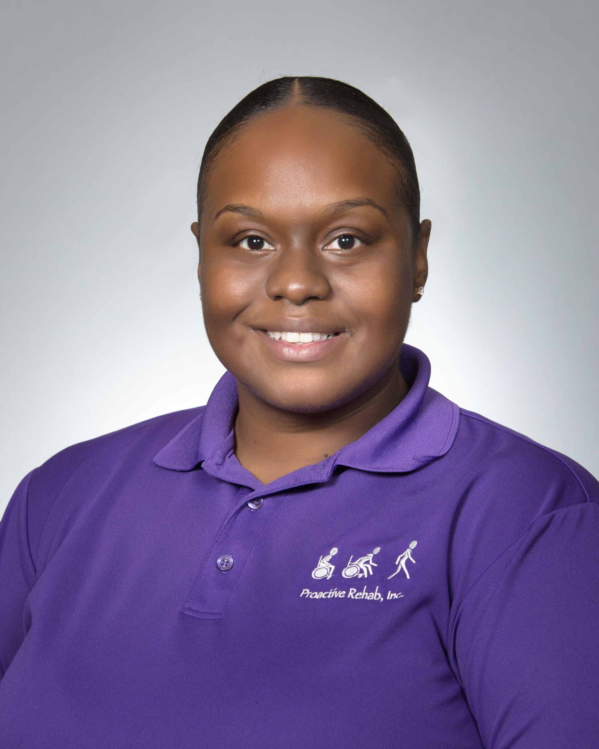 Person smiling in a purple polo shirt against a gray background.