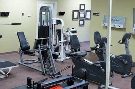 Small gym room with exercise machines, a treadmill, and wall mirrors.