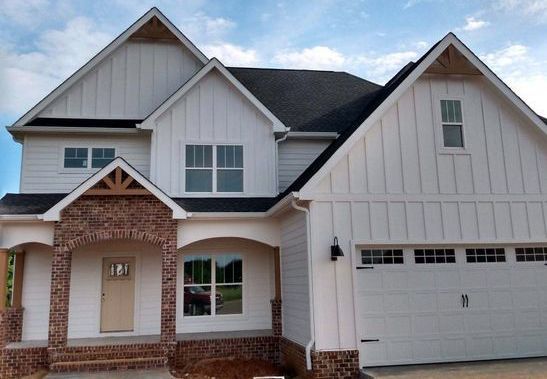 A large white house with a black roof and a garage