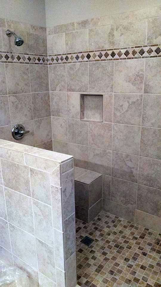 A bathroom with a walk in shower and a bench.