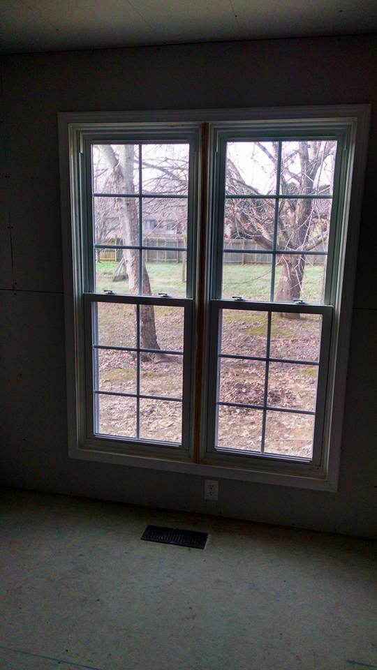 A room with two windows and a view of a yard.