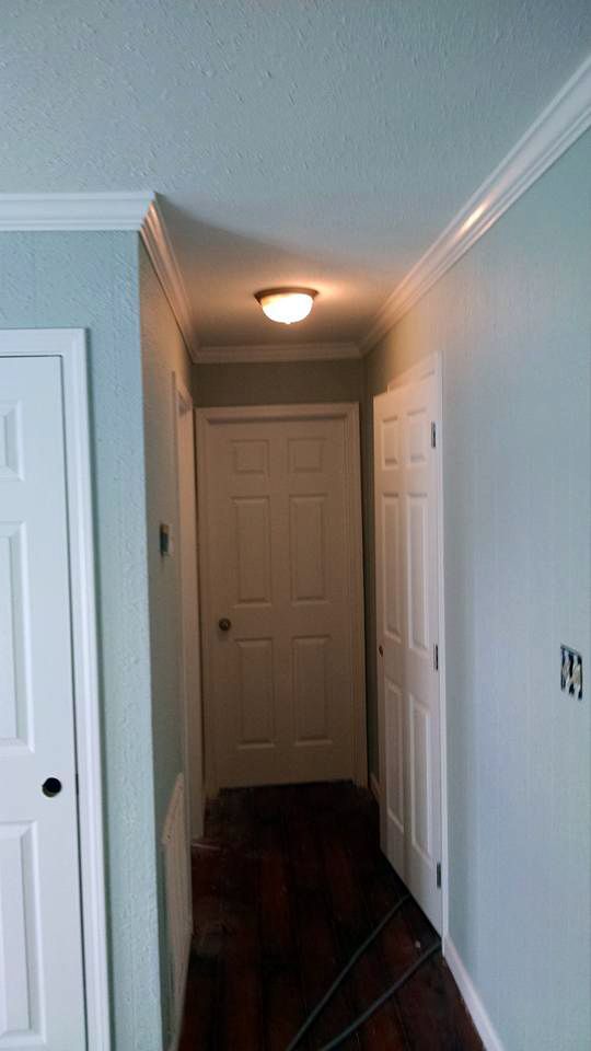 A hallway with hardwood floors and white doors in a house.