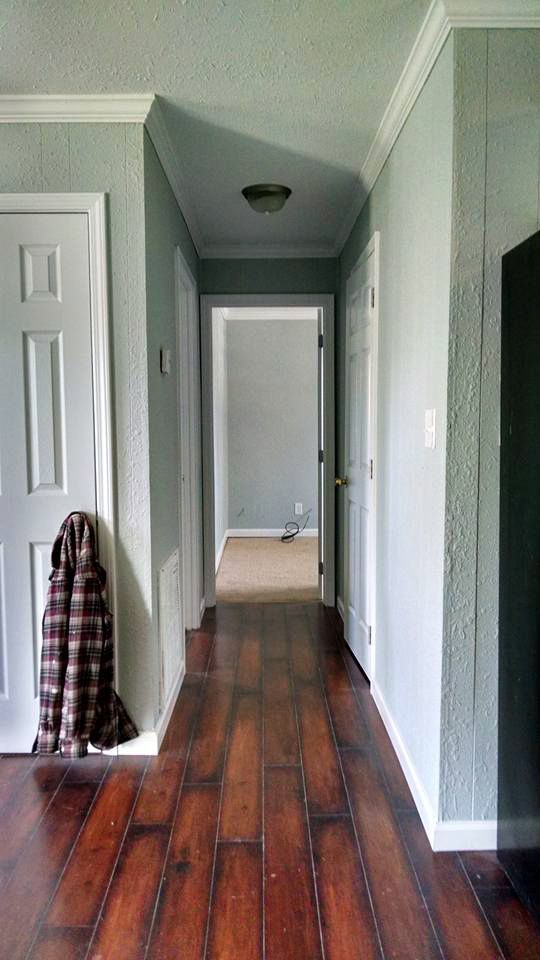 A hallway with hardwood floors and a coat hanging on the wall.