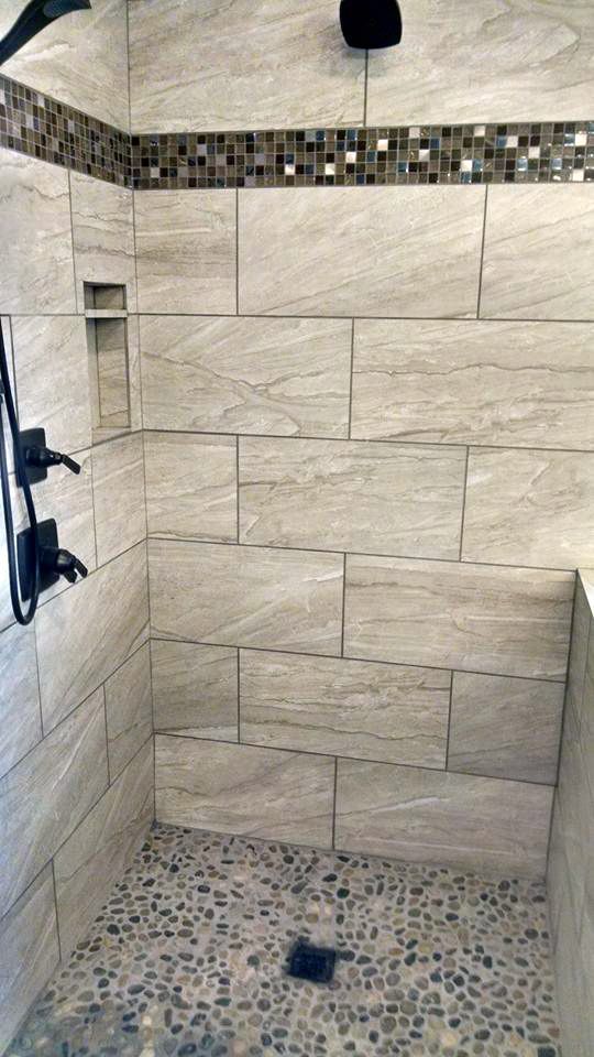 A walk in shower with tiled walls and a tiled floor.
