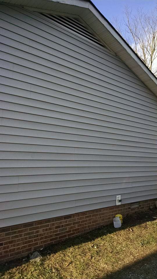 The side of a house with white siding and a brick foundation.