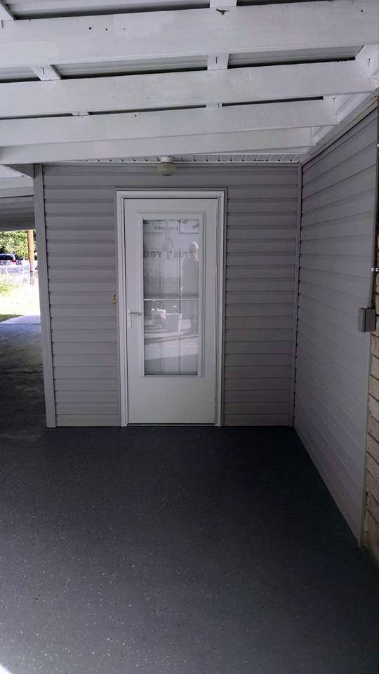 A gray house with a white door and a glass door.