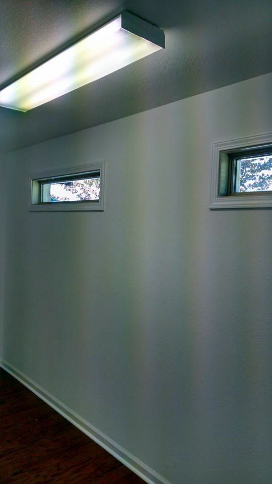 A room with two windows and a light on the ceiling.