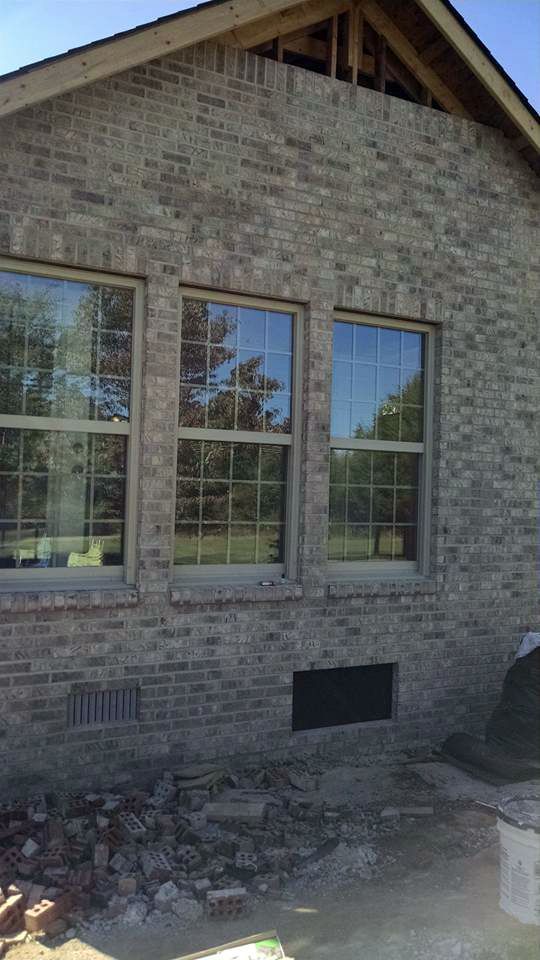 A brick building with two windows on the side of it.